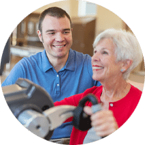 a smiling rehab nurse assisting an elderly woman in the rehab gym